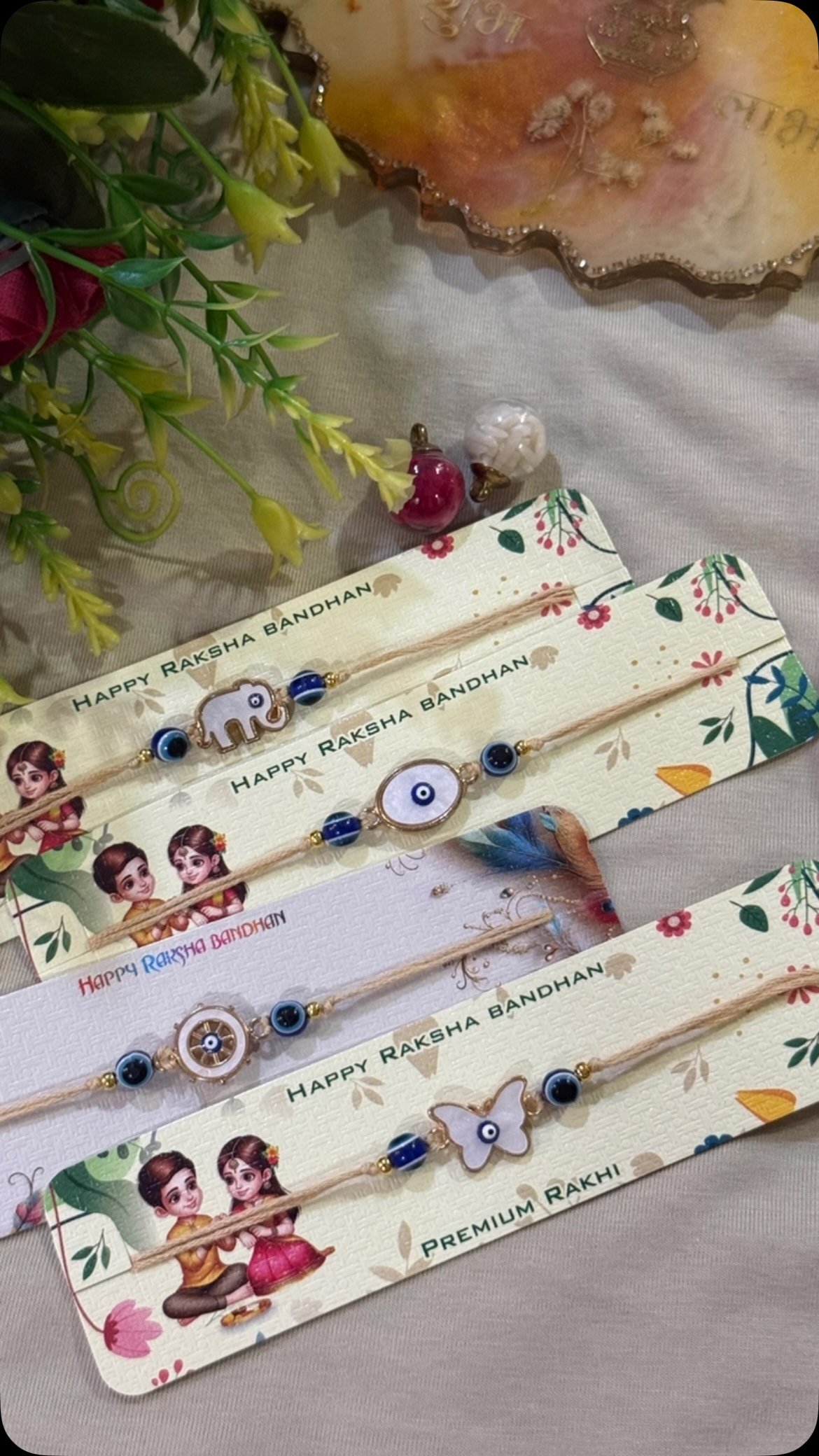 Set of four kids rakhis with elephant, evil eye, wheel and butterfly charms